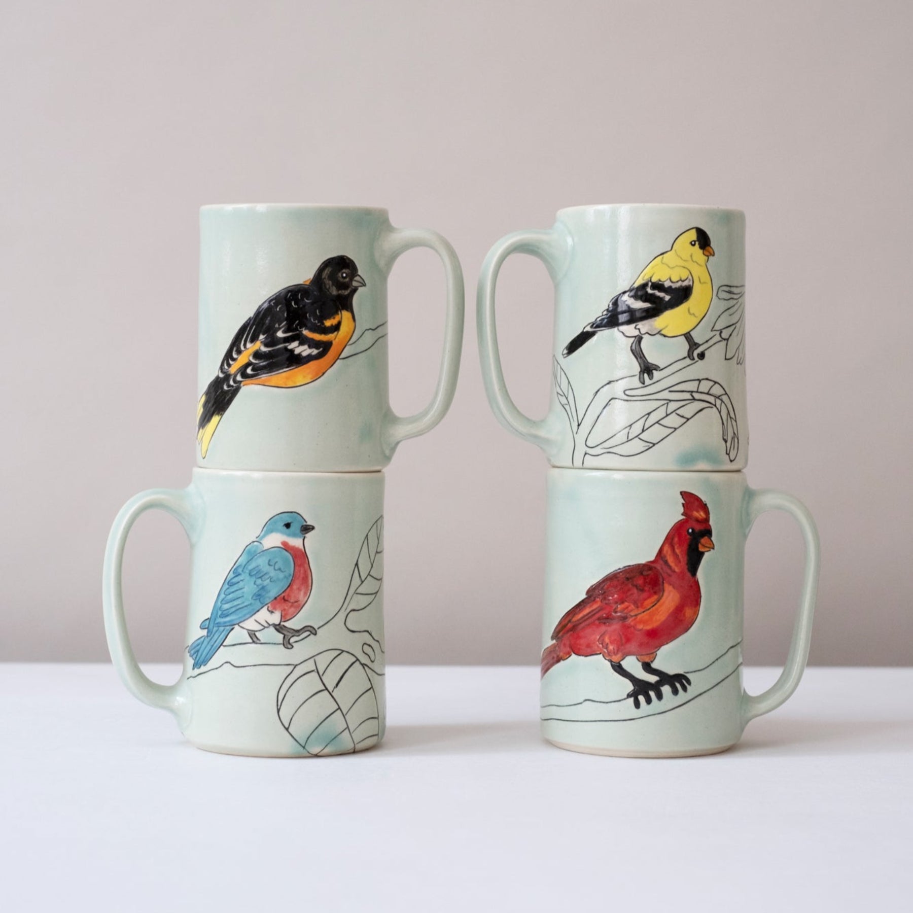 Set of four mugs with bird illustrations on a light background