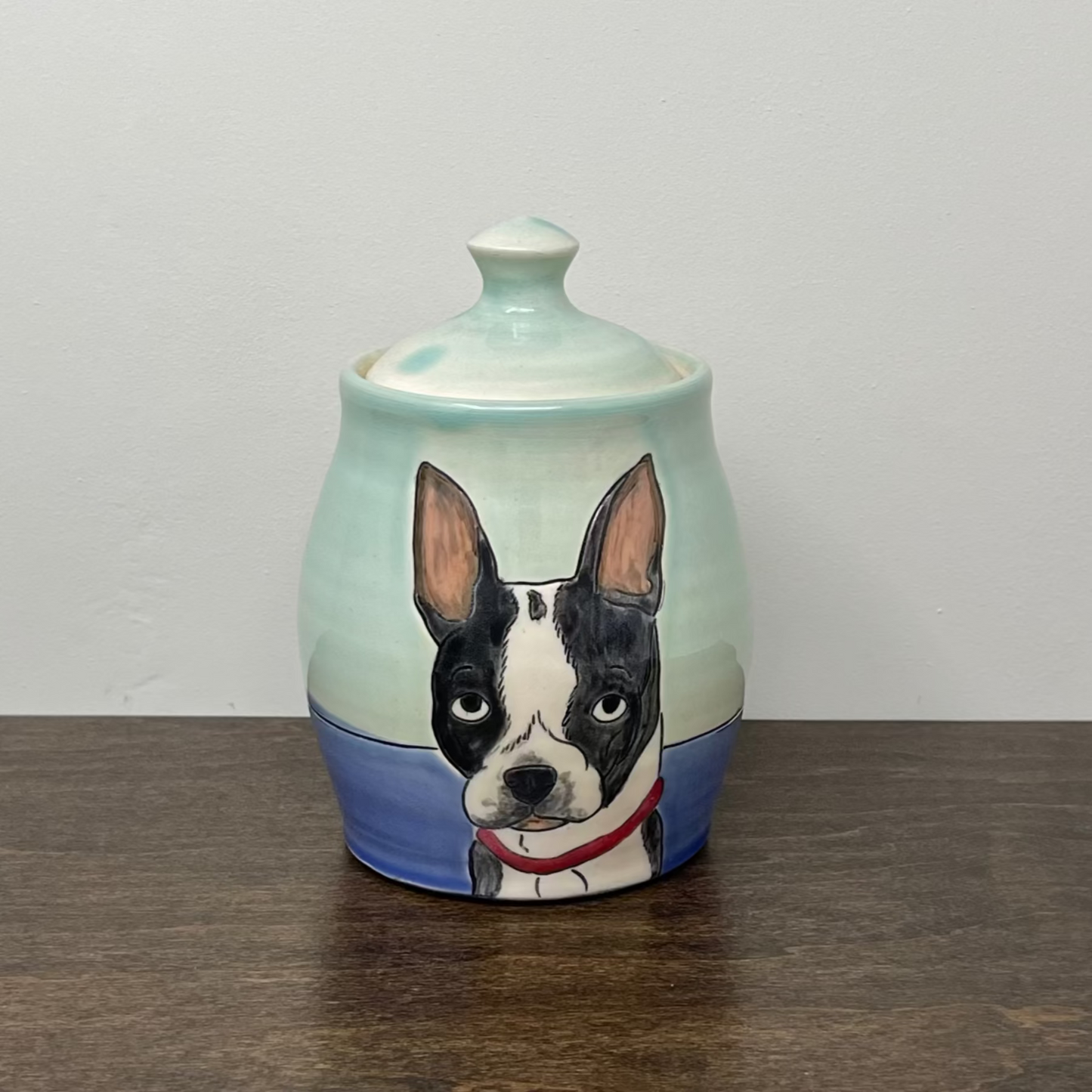 Ceramic jar with a dog illustration on a wooden surface and white background