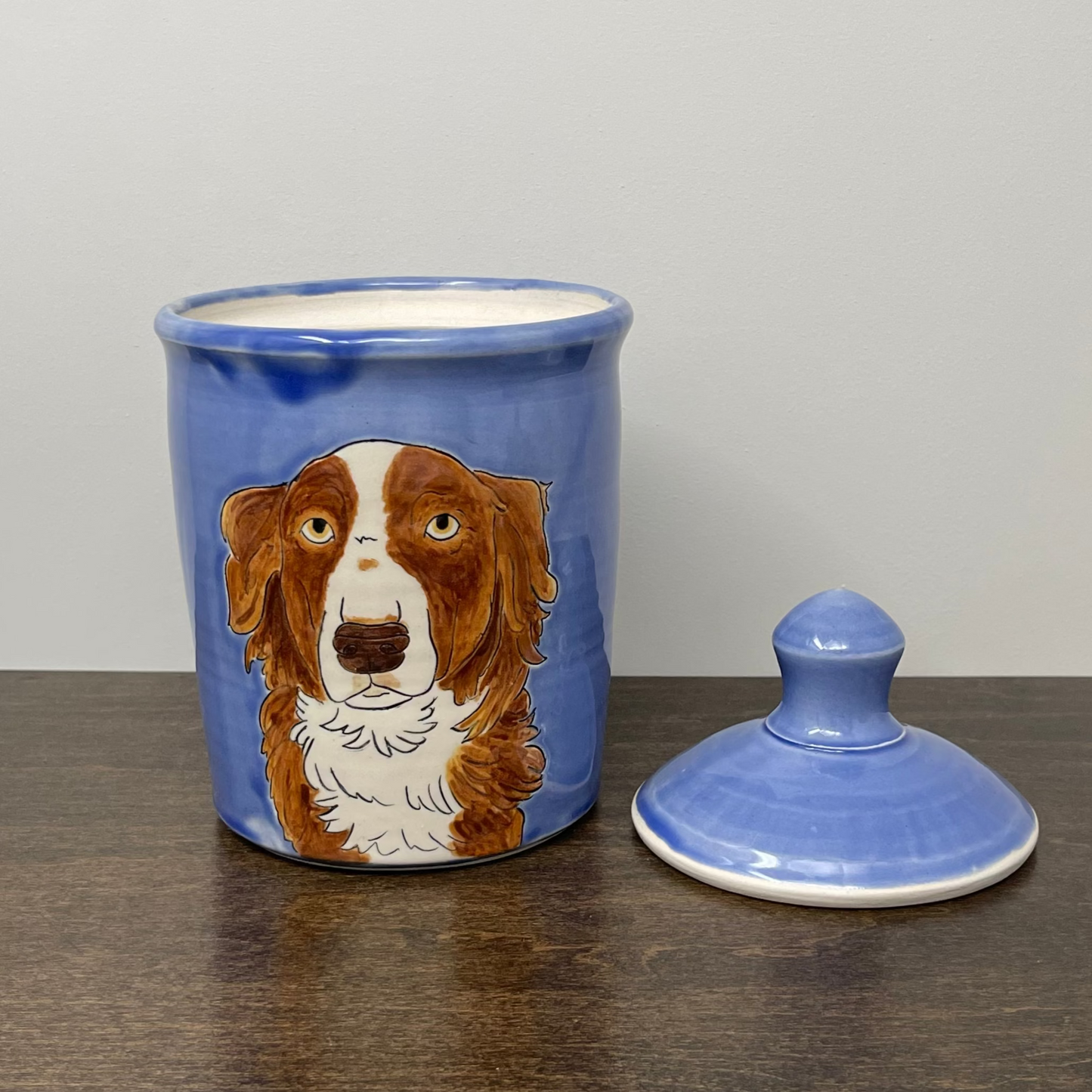 Blue ceramic jar with a dog illustration on a wooden surface