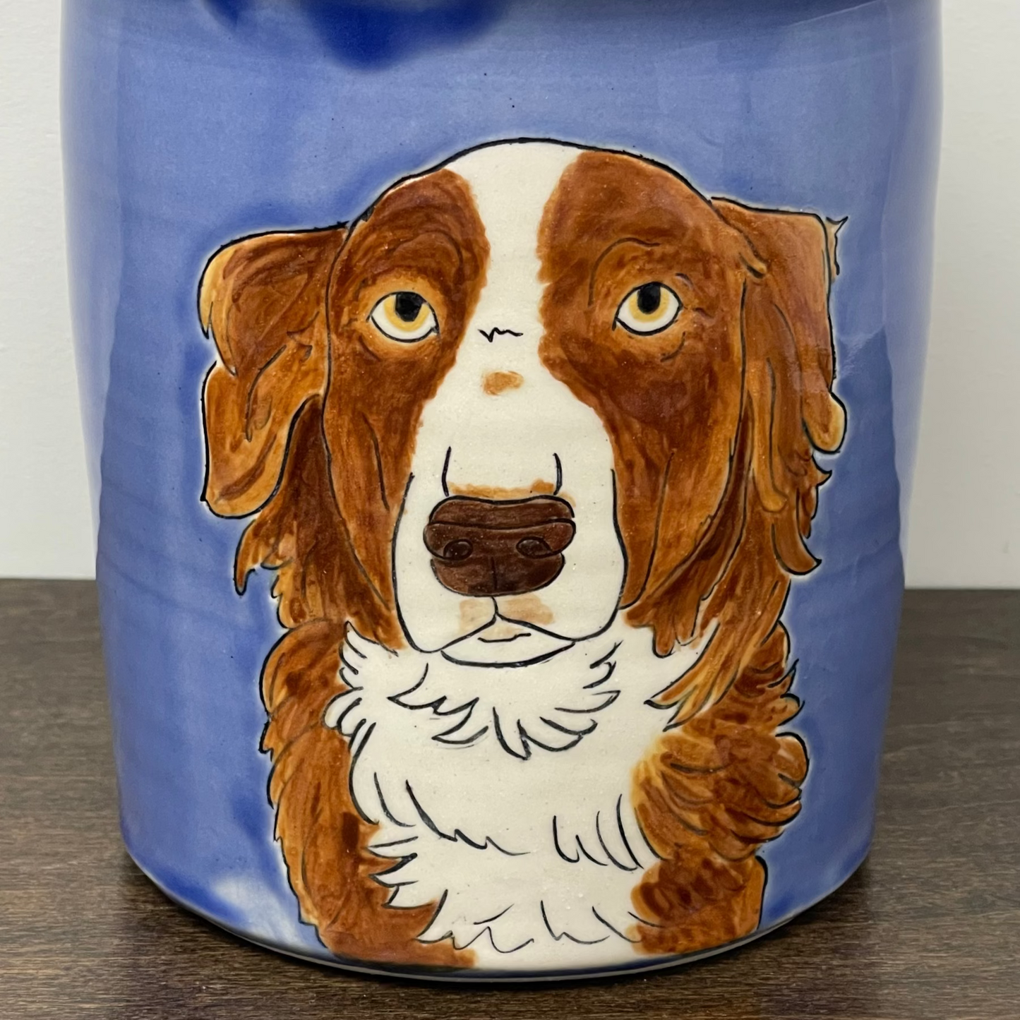 Ceramic jar with a brown and white dog illustration on a blue background