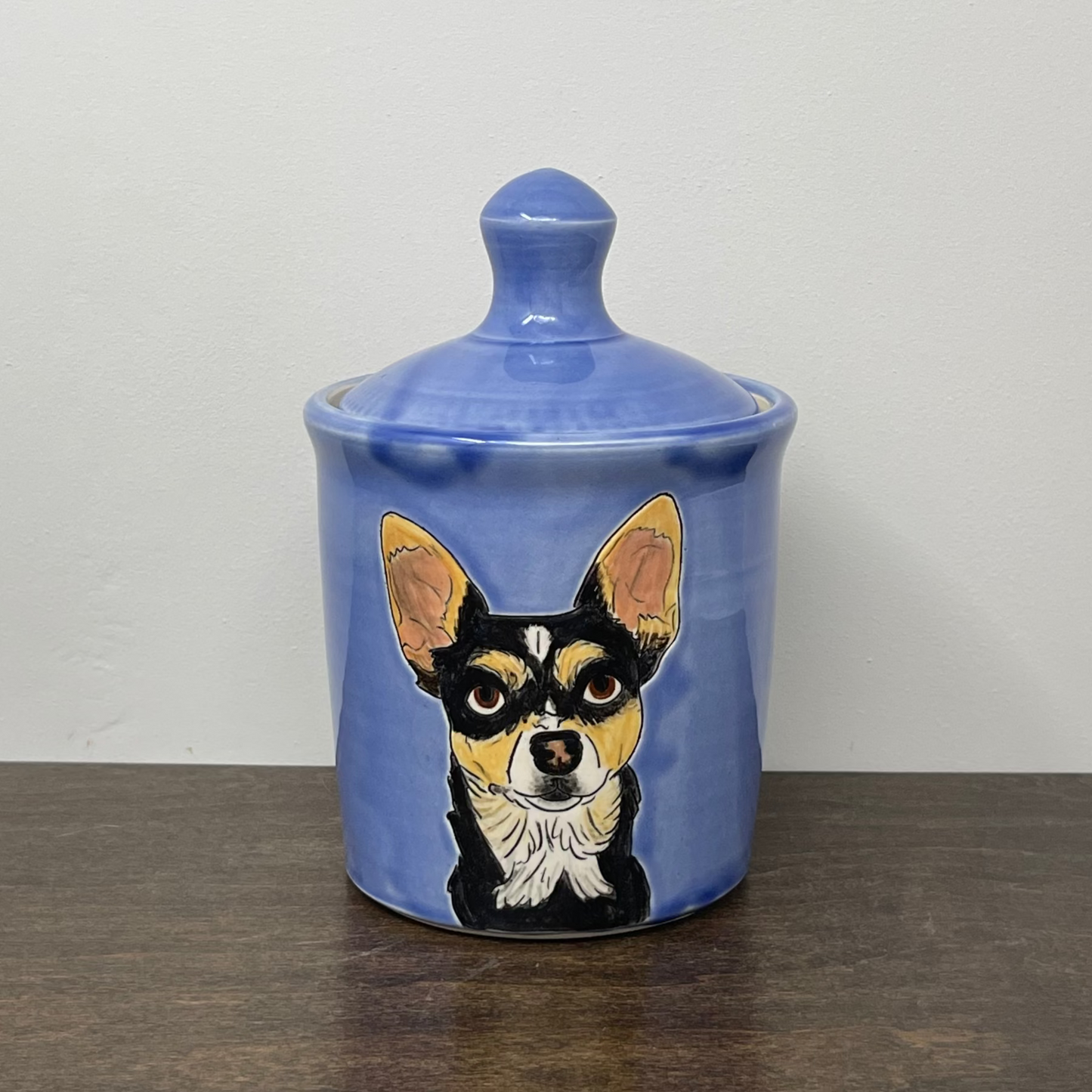 Ceramic jar with a dog illustration on a wooden surface and white background