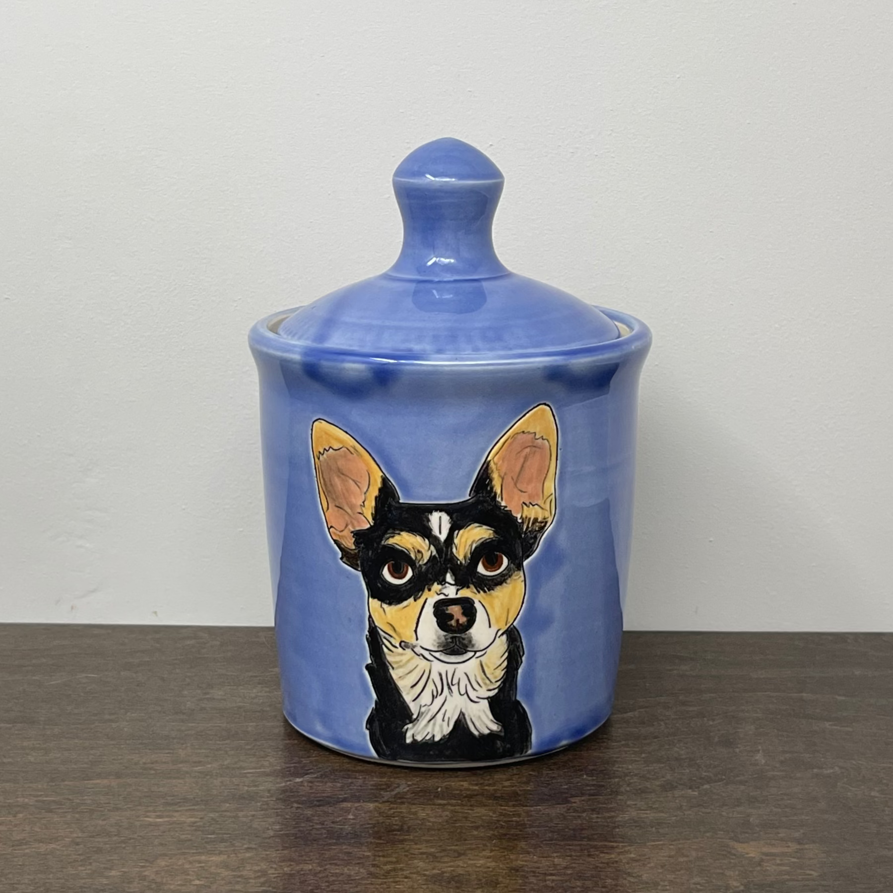 Ceramic jar with a dog illustration on a wooden surface and white background