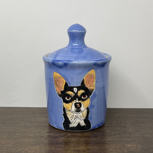 Ceramic jar with a dog illustration on a wooden surface and white background