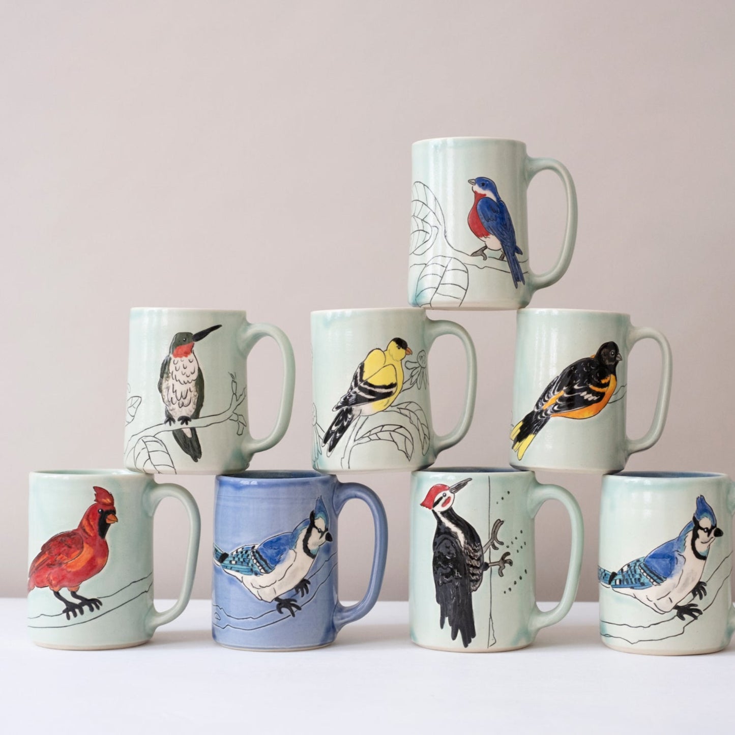 Set of ceramic mugs with bird illustrations on a light background