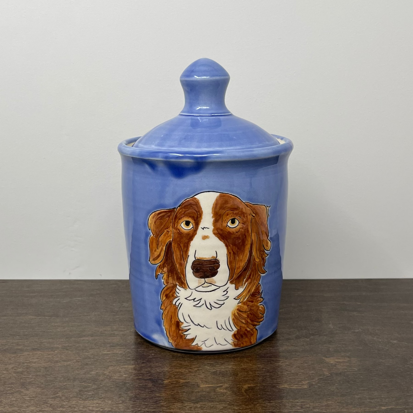 Blue ceramic jar with a dog illustration on a wooden surface